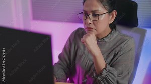 Close-up of a freelance web designer sitting at a desk in the evening working. Wondering about unusual behavior of code on a laptop computer? Write binary JavaScript code on your workstation at work.