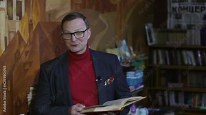 portrait of a businessman talking to the camera with a book in his hands about success and how to become successful. video chat for a remote interview