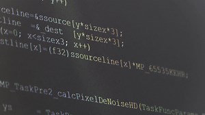Computer Source Code scrolls on a screen.