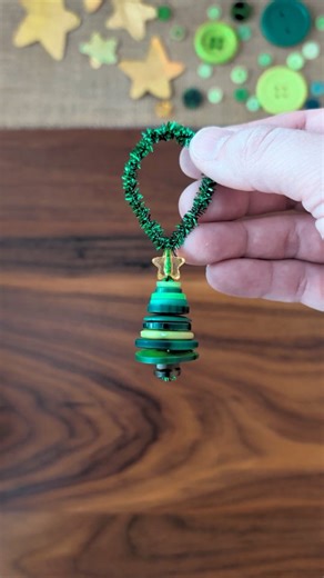 Button Christmas Tree Ornament 🎄 We went through our button jar finding all the green buttons for this craft! To make this Christmas tree ornament, fold a pipe cleaner in half and thread on a couple small brown buttons for the base of the tree. Add green buttons from largest to smallest and a star bead on top. Twist the remaining pipe cleaner into a loop for an ornament hanger. #kidcraft #easycraft #christmascrafts #diychristmas | Studio Rosie